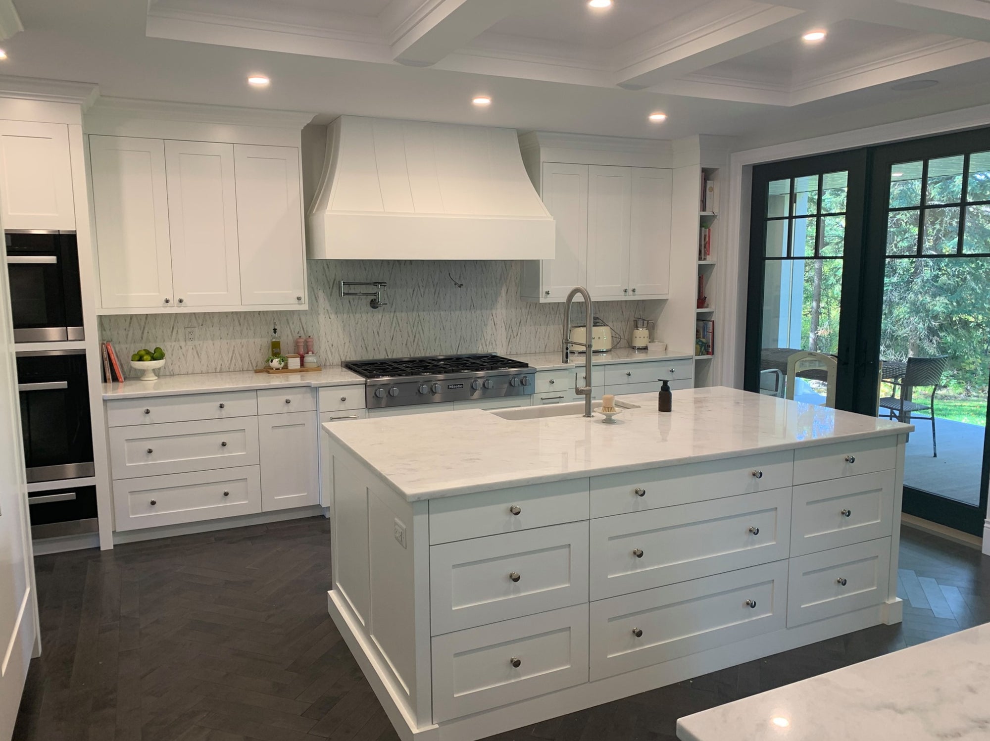 Custom white kitchen with a large island and finely detailed cabinetry by D.R. Sales Woodworking