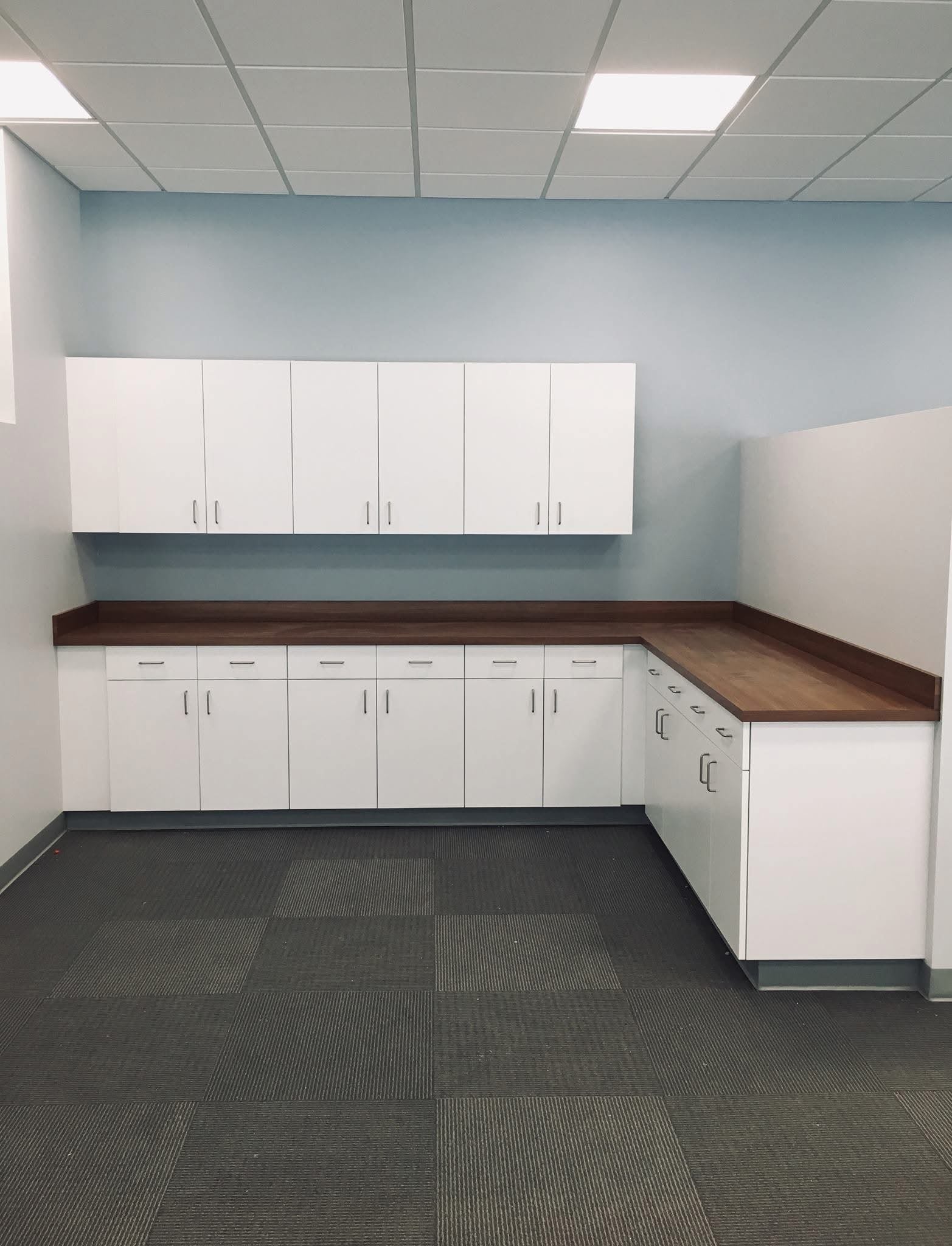 Commercial kitchenette with durable white cabinetry and wood look countertops